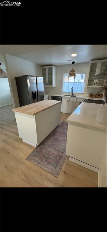 kitchen featuring sink, a center island, stainless steel refrigerator with ice dispenser, light hardwood / wood-style floors, and white cabinets