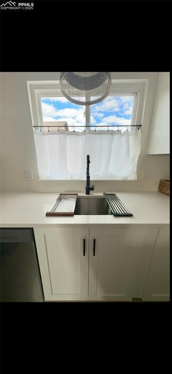 kitchen with white cabinetry, black dishwasher, and sink