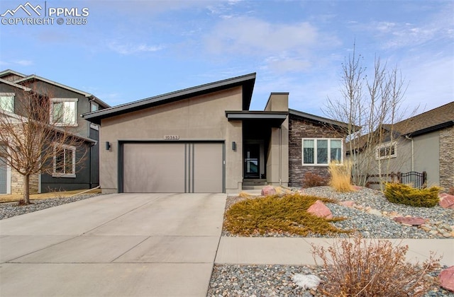 view of front of property featuring an attached garage, stone siding, concrete driveway, and stucco siding