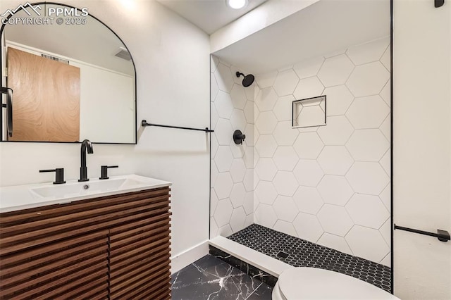 bathroom featuring tiled shower, vanity, and toilet