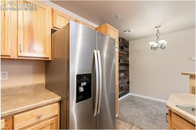 kitchen with light brown cabinetry, light carpet, stainless steel fridge, a notable chandelier, and pendant lighting