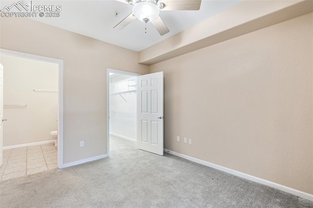 unfurnished bedroom featuring connected bathroom, a spacious closet, ceiling fan, light carpet, and a closet