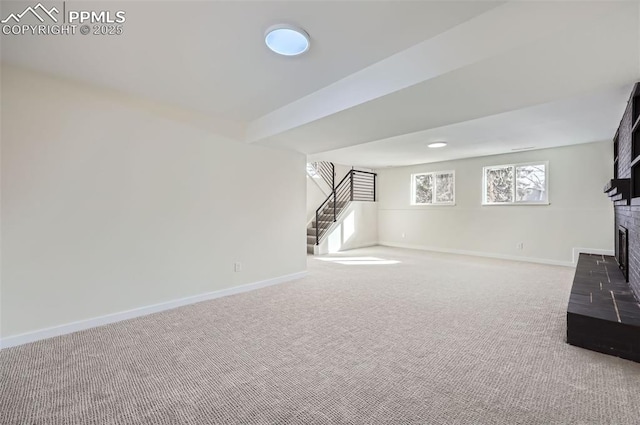 unfurnished living room with a brick fireplace, carpet floors, and beam ceiling