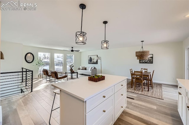 kitchen featuring white cabinetry, a kitchen island, pendant lighting, and light hardwood / wood-style floors