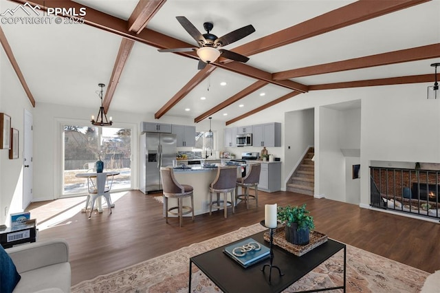 living room featuring dark hardwood / wood-style flooring, ceiling fan with notable chandelier, and lofted ceiling with beams