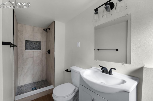 bathroom with a tile shower, vanity, and toilet