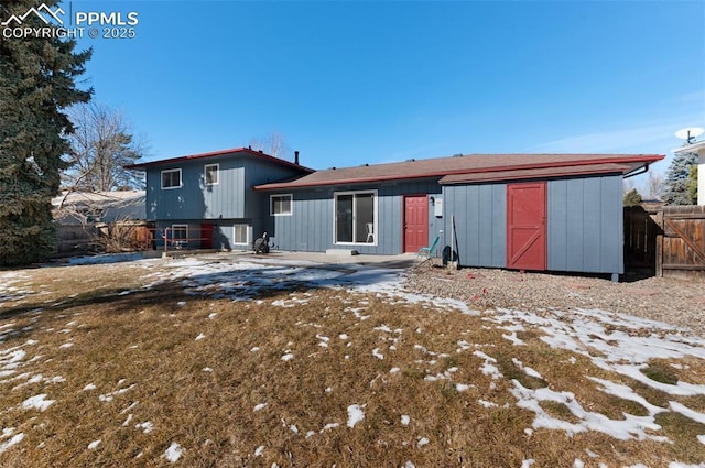 snow covered rear of property featuring a lawn and a storage shed