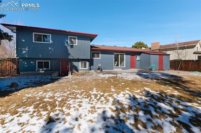 snow covered rear of property with a patio area