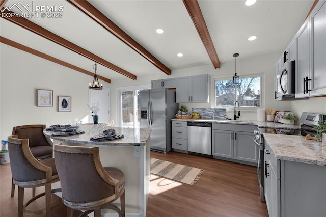 kitchen with stainless steel appliances, a kitchen island, sink, and pendant lighting