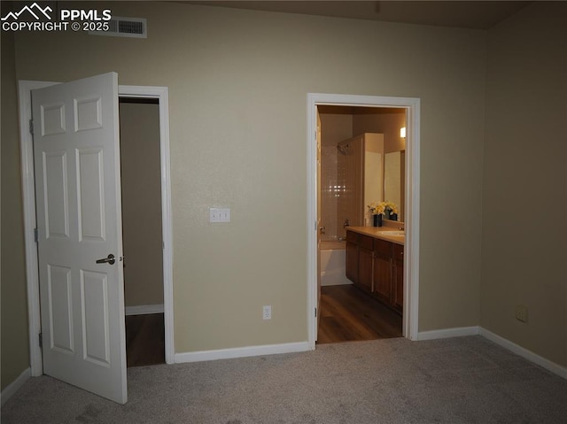 unfurnished bedroom featuring sink, ensuite bath, and carpet flooring