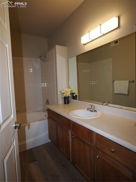 bathroom with vanity, hardwood / wood-style flooring, and tiled shower / bath combo