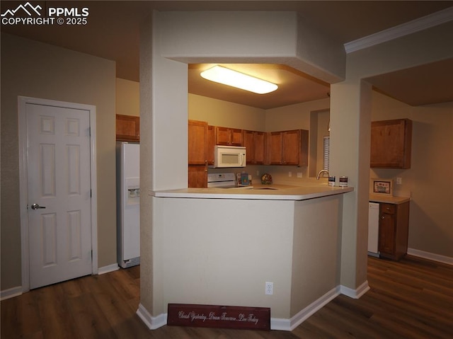 kitchen featuring dark wood-type flooring, white appliances, crown molding, and kitchen peninsula