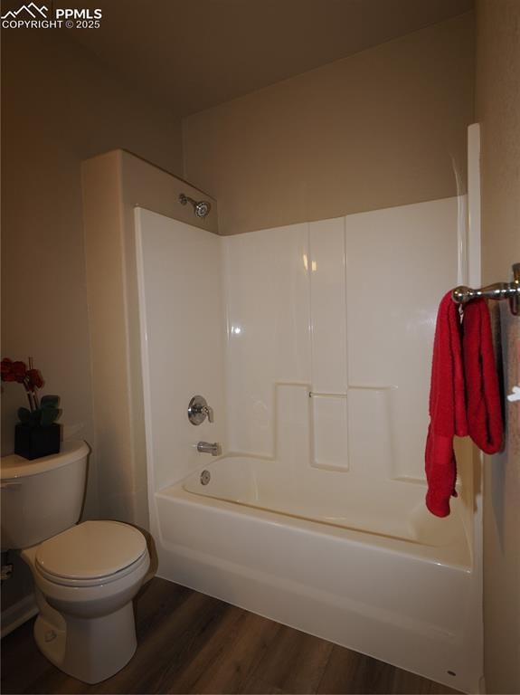 bathroom featuring hardwood / wood-style flooring, shower / washtub combination, and toilet