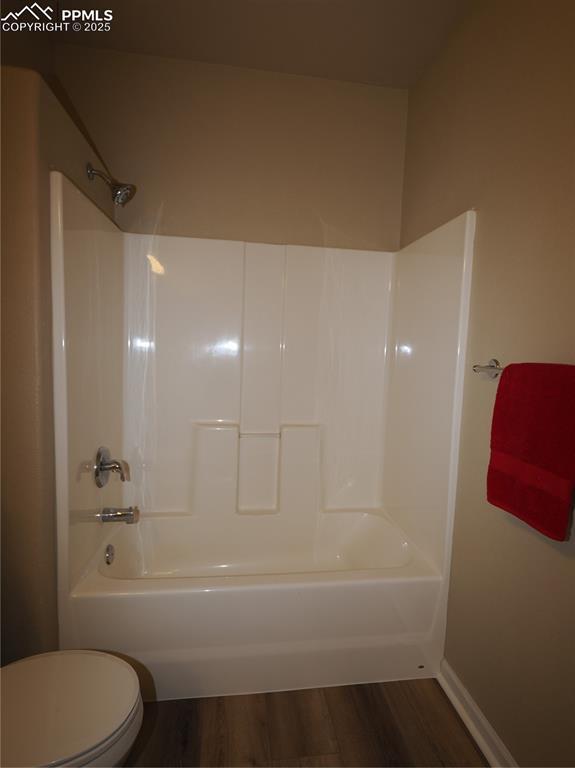 bathroom with hardwood / wood-style flooring, toilet, and shower / bathing tub combination