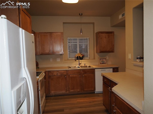 kitchen with hanging light fixtures, dark hardwood / wood-style flooring, sink, and white appliances