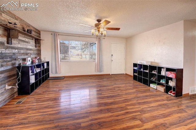 369 G St, Penrose, CO 81240 - living room featuring dark wood-type flooring, ceiling fan, a textured ceiling, and wood walls