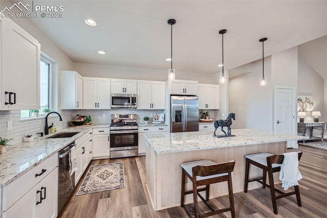 kitchen with sink, stainless steel appliances, white cabinets, and a kitchen island