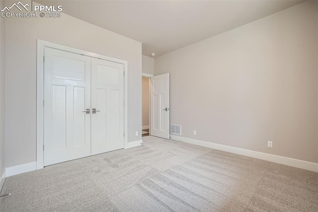 unfurnished bedroom with light colored carpet and a closet