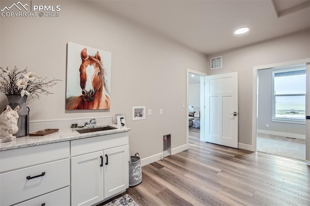 washroom with cabinets, light hardwood / wood-style floors, hookup for a washing machine, and sink