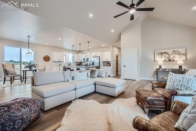 living room featuring hardwood / wood-style floors, high vaulted ceiling, sink, and ceiling fan