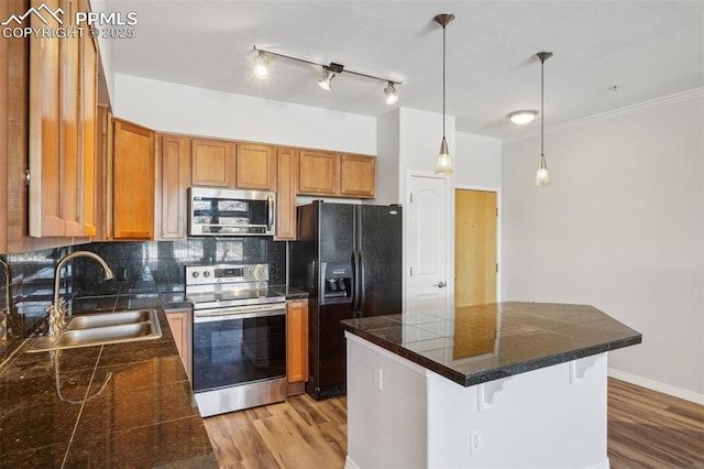 kitchen with a kitchen bar, sink, pendant lighting, stainless steel appliances, and backsplash