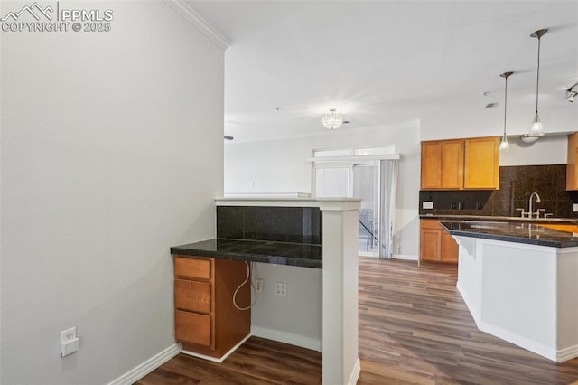 kitchen featuring hanging light fixtures, backsplash, a kitchen bar, and kitchen peninsula