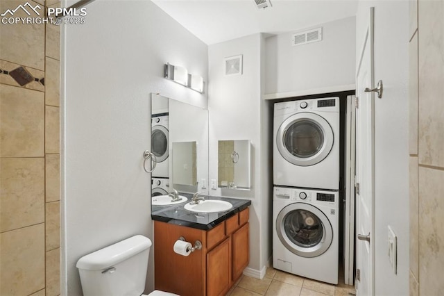 bathroom with tile patterned floors, stacked washer / dryer, toilet, and vanity