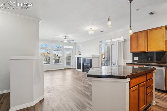 kitchen featuring tasteful backsplash, a center island, ornamental molding, dishwasher, and hardwood / wood-style floors