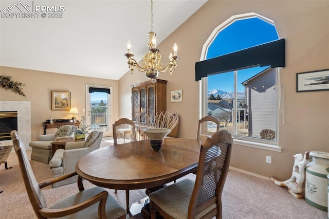 dining space with a notable chandelier, a fireplace, light colored carpet, and high vaulted ceiling