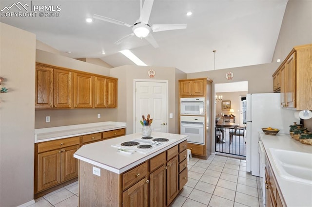 kitchen with light tile patterned floors, white appliances, ceiling fan, a kitchen island, and vaulted ceiling