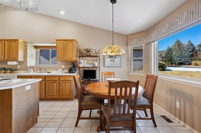 kitchen with lofted ceiling, sink, light tile patterned floors, and decorative light fixtures