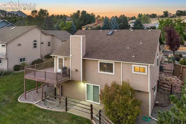 back house at dusk featuring a balcony and a yard