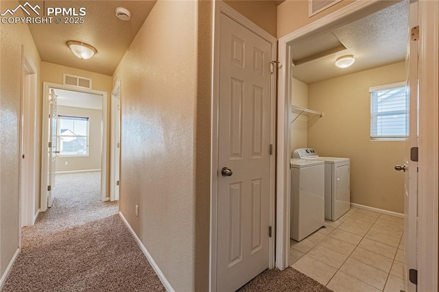 laundry room featuring light colored carpet, washer and dryer, and a textured ceiling