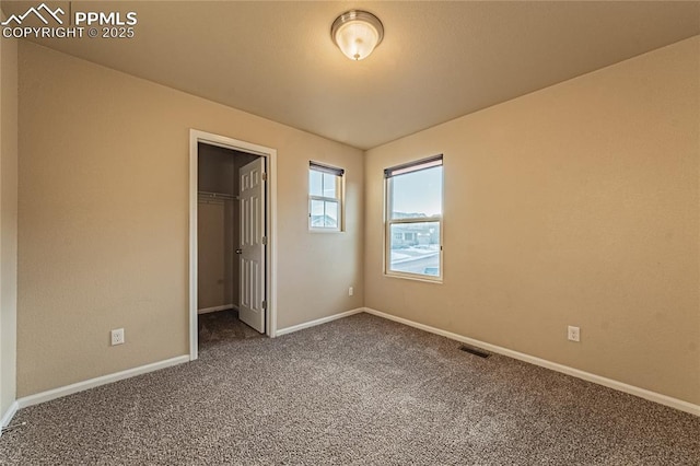 unfurnished bedroom with a spacious closet, a closet, and carpet