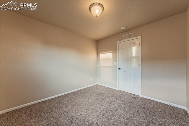 empty room with a textured ceiling and carpet