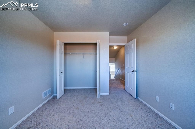 unfurnished bedroom with carpet floors, a textured ceiling, and a closet