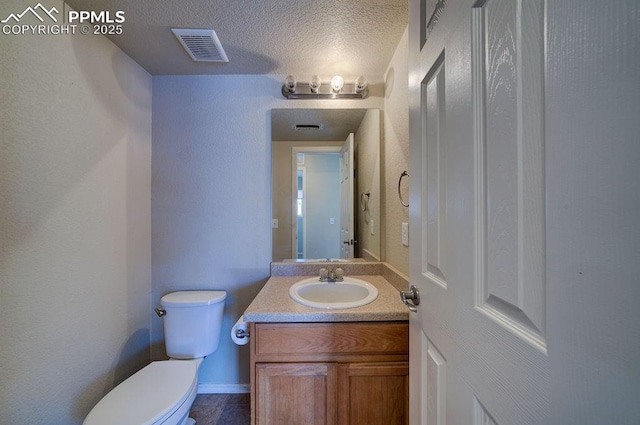 bathroom featuring vanity, toilet, and a textured ceiling