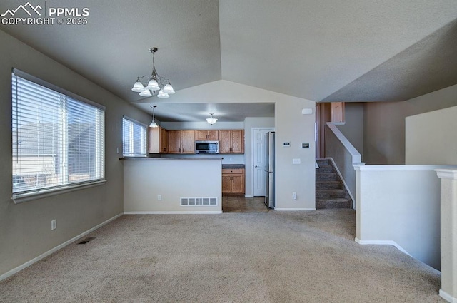 kitchen featuring appliances with stainless steel finishes, hanging light fixtures, a notable chandelier, carpet floors, and kitchen peninsula