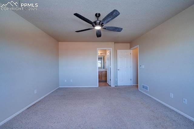 unfurnished bedroom with ceiling fan, connected bathroom, light carpet, and a textured ceiling