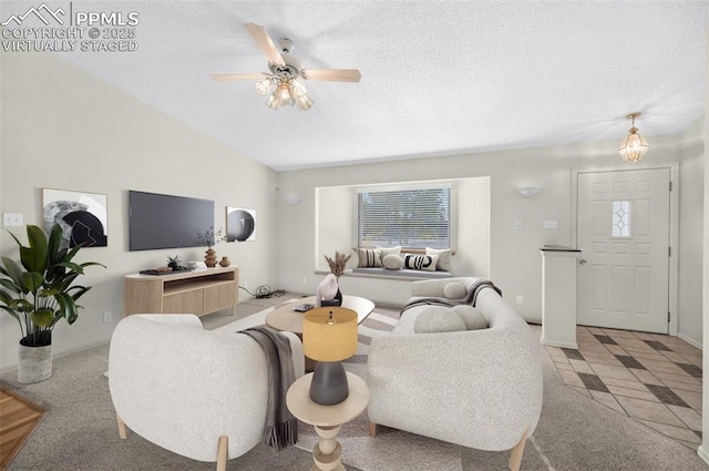 tiled living room with ceiling fan, vaulted ceiling, and a textured ceiling