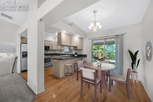 kitchen featuring lofted ceiling, a breakfast bar area, hanging light fixtures, light wood-type flooring, and appliances with stainless steel finishes