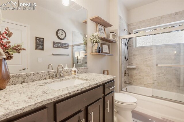 full bathroom with toilet, vanity, and bath / shower combo with glass door