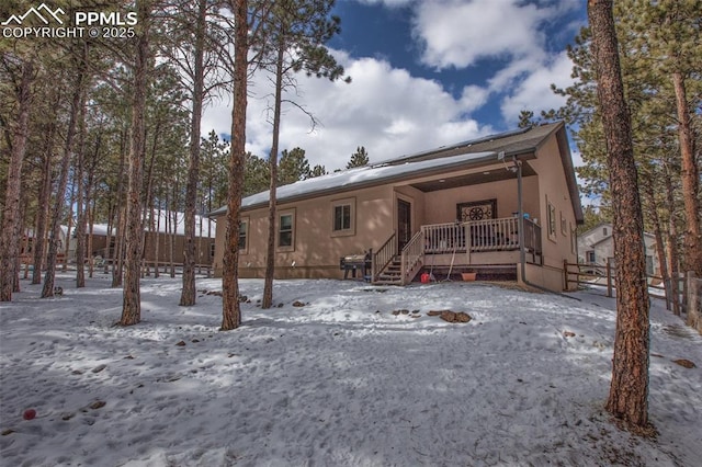 snow covered house featuring a wooden deck