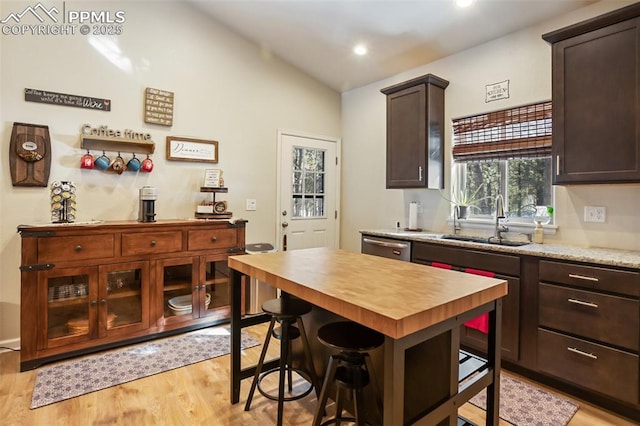 kitchen featuring vaulted ceiling, a breakfast bar, sink, dark brown cabinets, and light hardwood / wood-style flooring