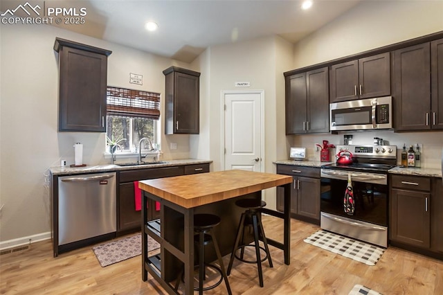 kitchen with sink, light hardwood / wood-style flooring, wooden counters, appliances with stainless steel finishes, and dark brown cabinetry