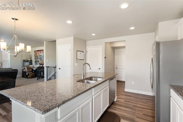 kitchen featuring stainless steel appliances, stone countertops, sink, and a center island with sink