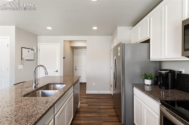 kitchen featuring appliances with stainless steel finishes, sink, dark stone countertops, and white cabinets