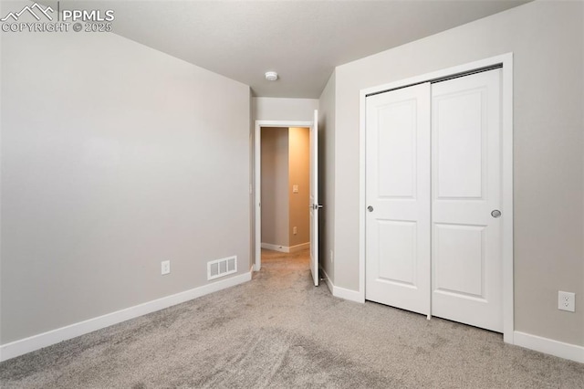 unfurnished bedroom featuring light colored carpet and a closet