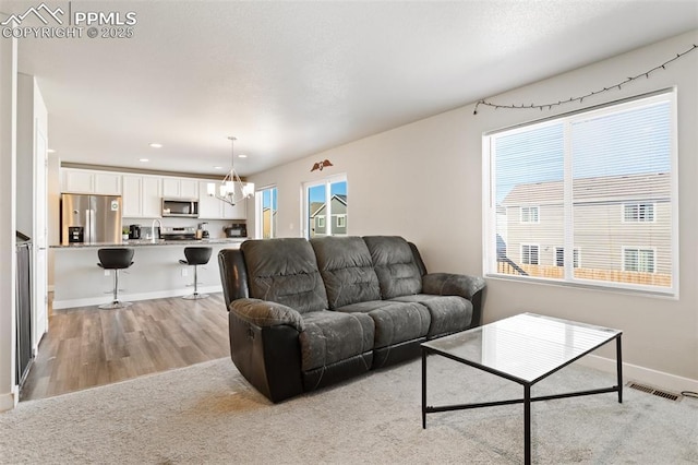 living room featuring sink, a notable chandelier, and light hardwood / wood-style flooring