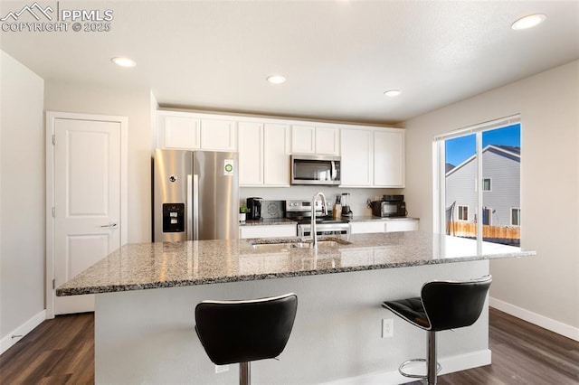 kitchen with an island with sink, appliances with stainless steel finishes, and white cabinets